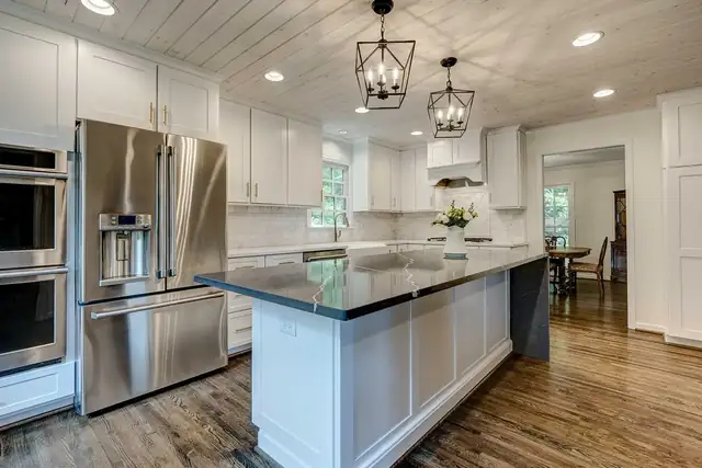 Mountain Brook kitchen remodel with white shaker cabinets, dark-topped island, lantern pendants, stainless double ovens and a planked ceiling