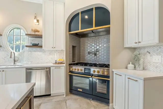 Hoover kitchen with an arched alcove framing a navy and brass range, hexagon tile backsplash and round window