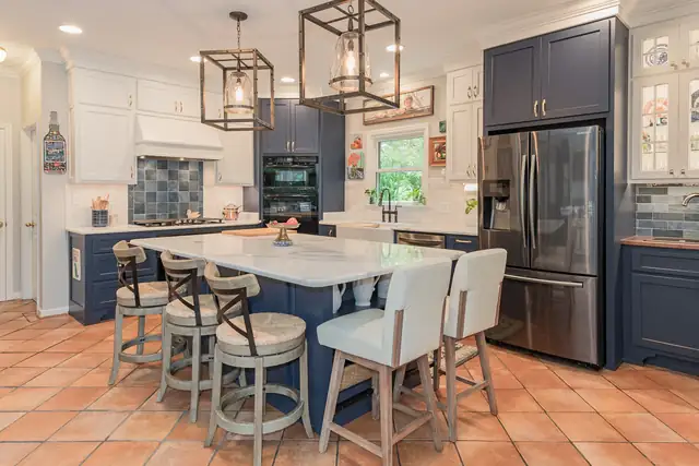 Homewood kitchen remodel with navy lower cabinets, white uppers, terracotta tile floor and iron cage pendants over the island